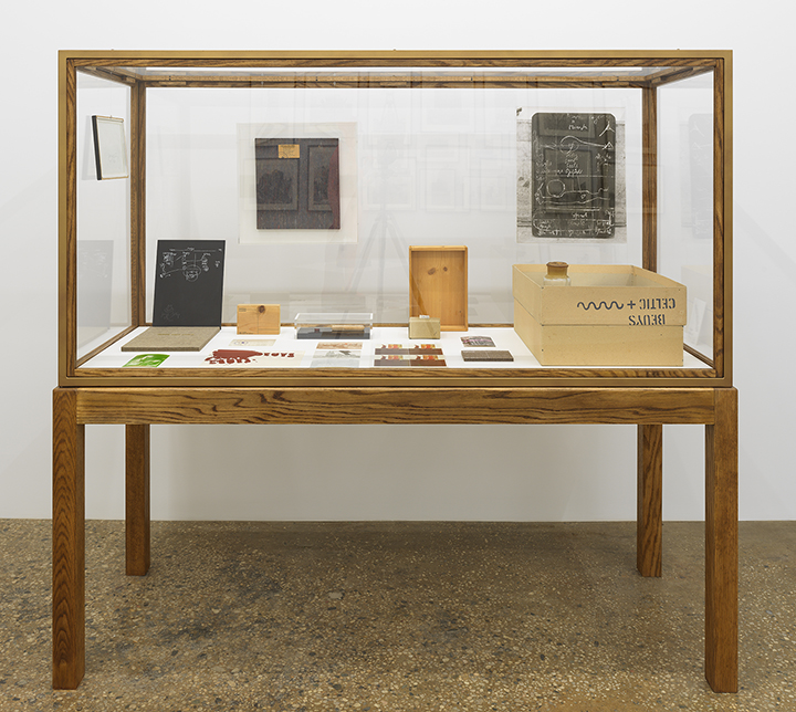 Wood and glass vitrine containing small sculptures and postcards