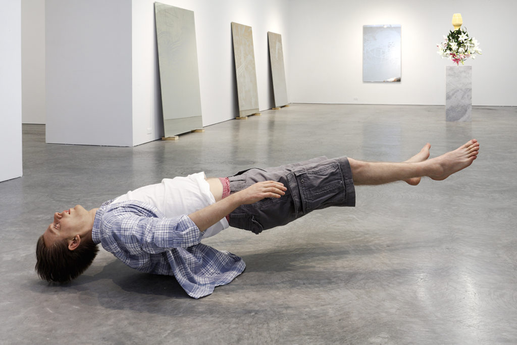 paintings and sculpture of levitating man in gallery