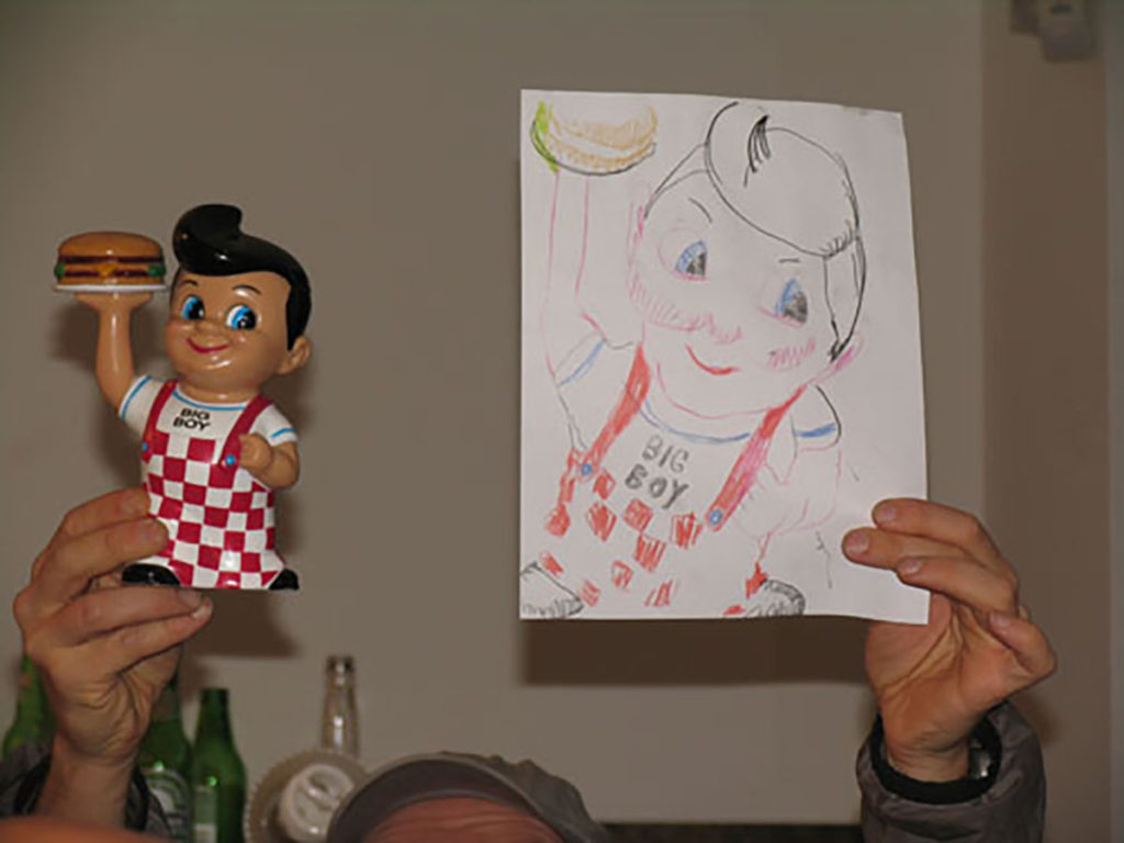 man holding up a doll and a drawing