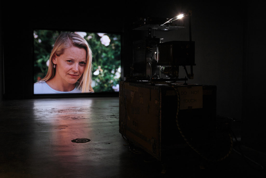 projection of a woman in a video in a dimly lit gallery