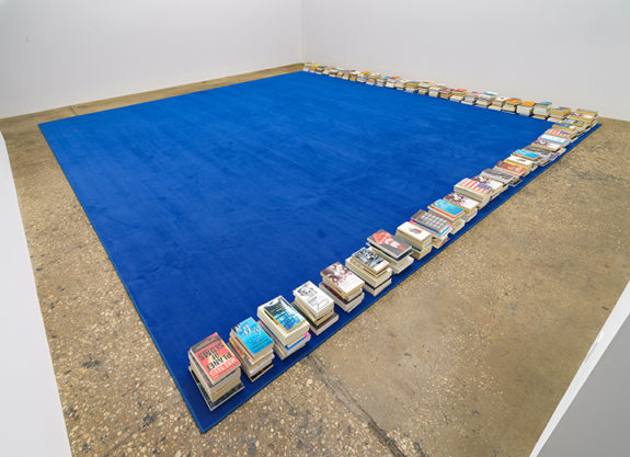 blue rug with piles of books at edges